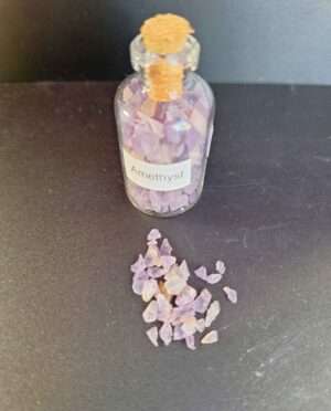Clear bottle filled with polished amethyst gemstone grains