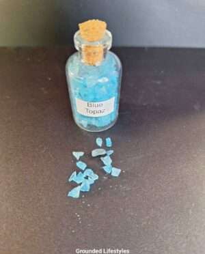 Clear bottle filled with polished blue topaz gemstone grains