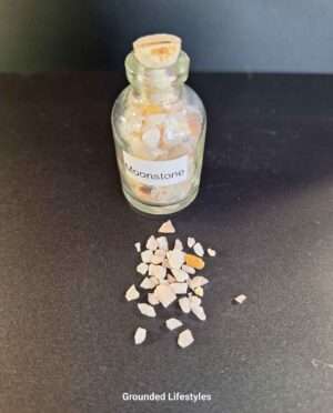 Clear glass bottle filled with polished moonstone gemstone grains