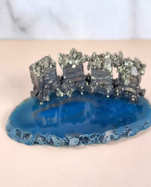 Pewter ore carts filled with pyrite sitting atop a blue agate slice