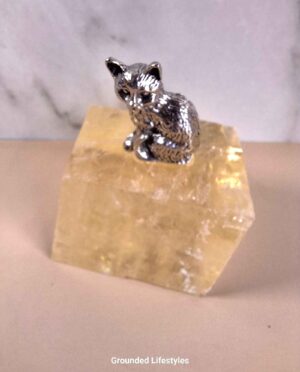 Handcrafted pewter cat sculpture sitting atop a translucent ice spar crystal