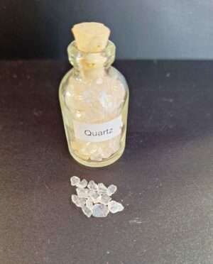 Clear glass bottle filled with polished clear quartz gemstone grains