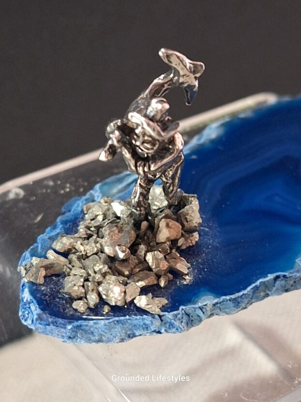 pewter miner with axe and pyrite grains displayed on polished agate slice
